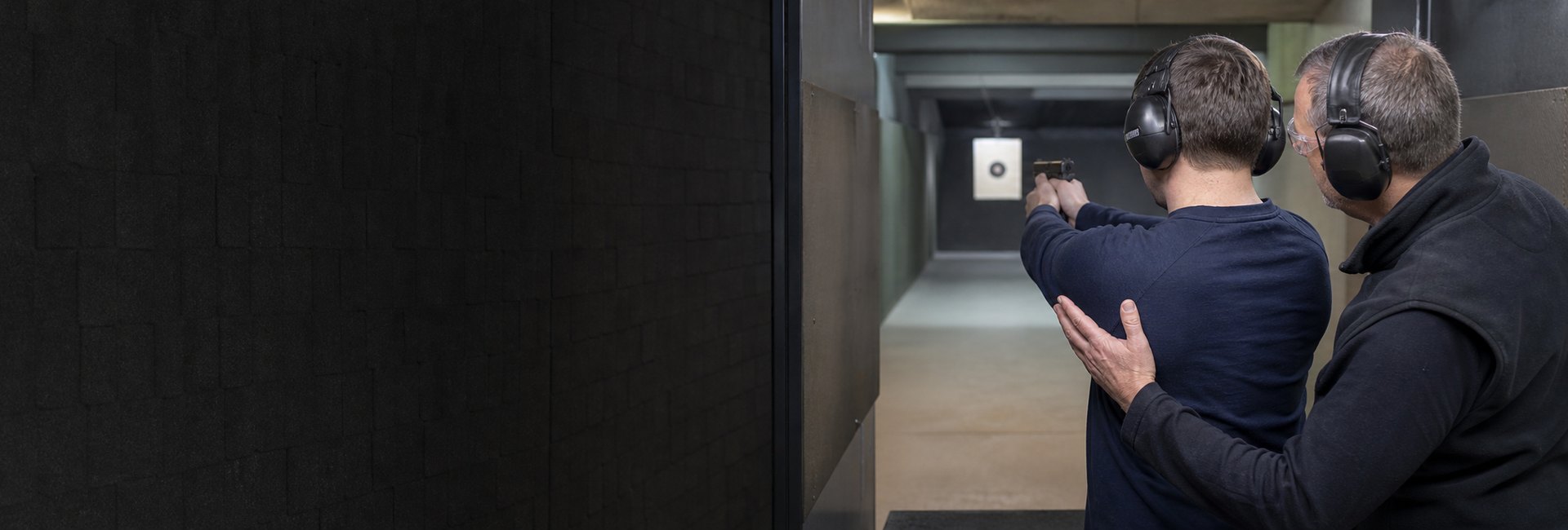 Ausbilder begleitet einen vollj&auml;hrigen Teilnehmer beim kontrollierten Schie&szlig;en auf einem Schie&szlig;stand